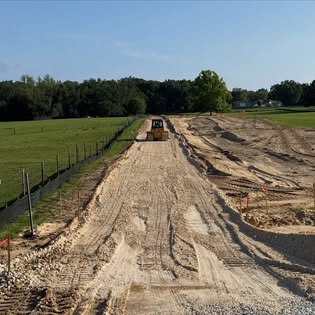 Dozer grading a road cut between pastures