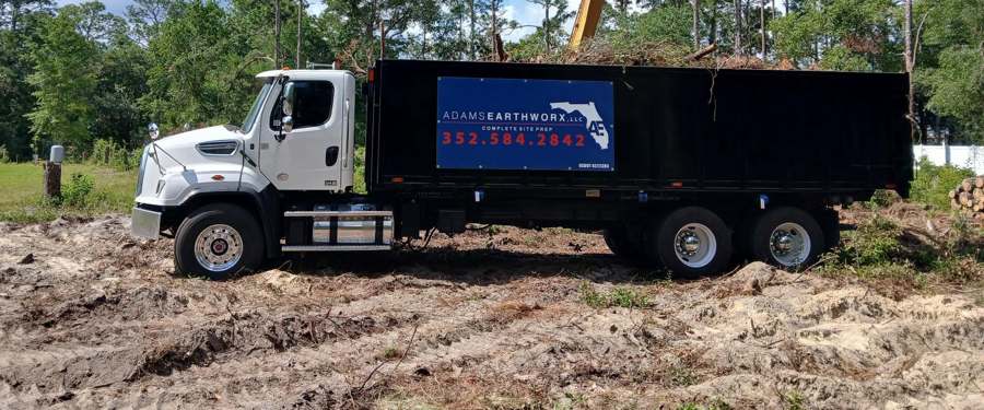 Adams Earthworx dump truck loaded with cleared debris in Brooksville FL